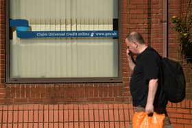 A man walks past a sign with the email address of ‘universal credit’ outside a Job Centre.