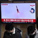 A man watches a television screen showing a news broadcast with file footage of a North Korean missile test, at a railway station in Seoul on December 31, 2022