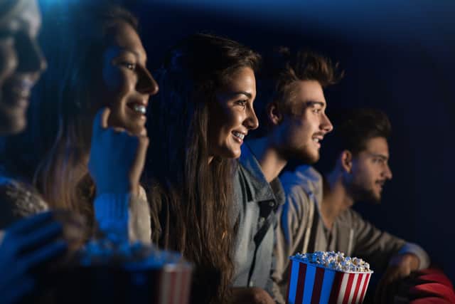 An audience of cinema goers enjoying popcorn - can you guess which of them is called Elizabeth? (Credit: Adobe)