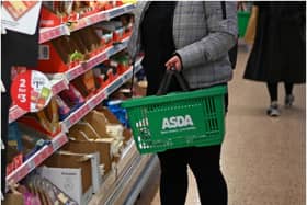 A shopper wearing a protective face covering to combat the spread of the coronavirus, chooses items off the shelves of an Asda supermarket in London on December 14, 2020. - With just over two weeks to go until Britain leaves the EU single market, preparations have been stepped up as fears grow about the impact of customs checks and congested ports. Concern is rising over the supply of perishable fresh fruit and vegetables, much of which is imported from EU countries. (Photo by Daniel LEAL / AFP) (Photo by DANIEL LEAL/AFP via Getty Images)