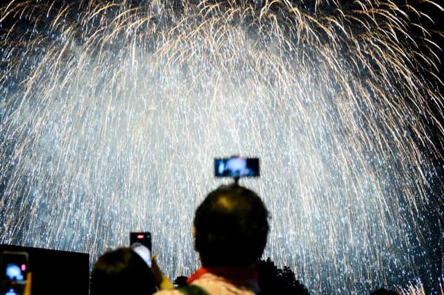 Person taking photo of a firework display. Photo: ANTHONY WALLACE/AFP via Getty Images