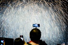 Person taking photo of a firework display. Photo: ANTHONY WALLACE/AFP via Getty Images