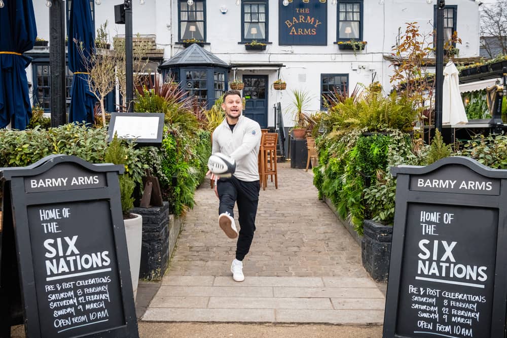 Former England rugby international Danny Care kicking a ball "into space" from outside the Greene King sport pub The Barmy Arms in Twickenham