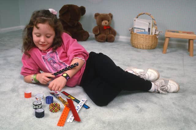 A child with a collection of slap bracelets, which were popular in the 1980s and early 90s