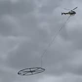 Helicopter carrying large metal circle.