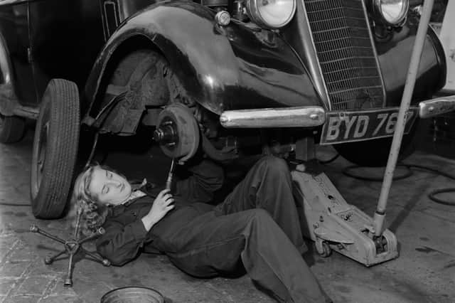 A mechanic works on a vehicle, with a car jack in place to raise it off the ground