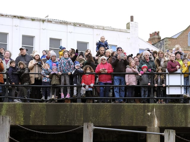 Children and their parents line the harbour side.