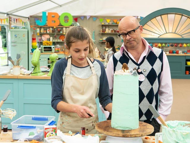 Eliza ices a creation while presenter Harry Hill looks on.