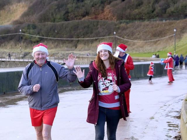 Two runners wave on their return to the finish line.