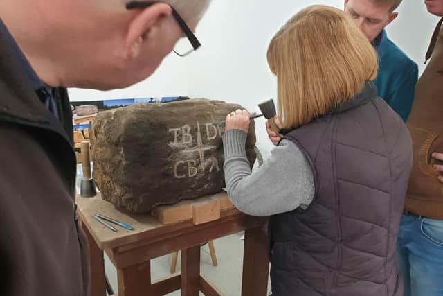 The Briggs men look on as Deanna chisels their stone