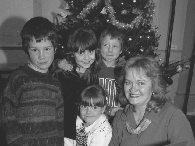 Hinderwell school teacher Jill Tiffany is pictured at her special leaving assembly with pupils, left to right, Isaac Sands, Rebecca Hunter, David Fallows, and seated Victoria Robinson. Jill holds her special leaving card made by the children. Photo taken in December 1997.