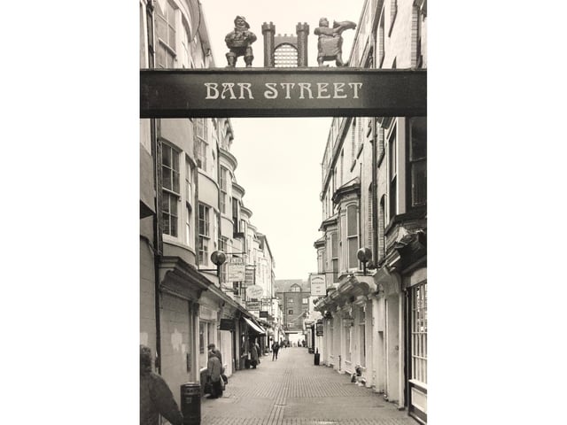 The street sign is still above the opening to the street, but the figures on top have been replaced with a circular shield.