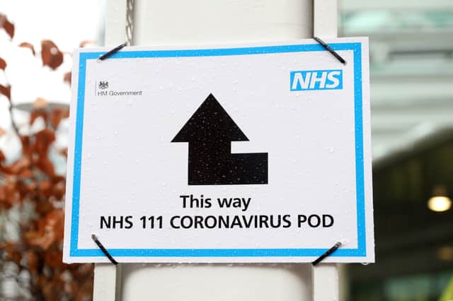 A sign directs patients towards an NHS 111 Coronavirus (COVID-19) Pod.
