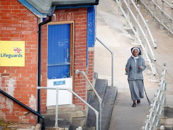 A woman walks along the sea front in Whitby, Yorkshire , after the introduction of measures to bring the country out of lockdown. Photo: PA