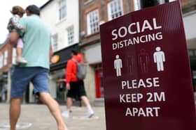 People walk past a social distancing sign, ahead of the re-opening of non-essential retailers in England on June 15. Photo: PA