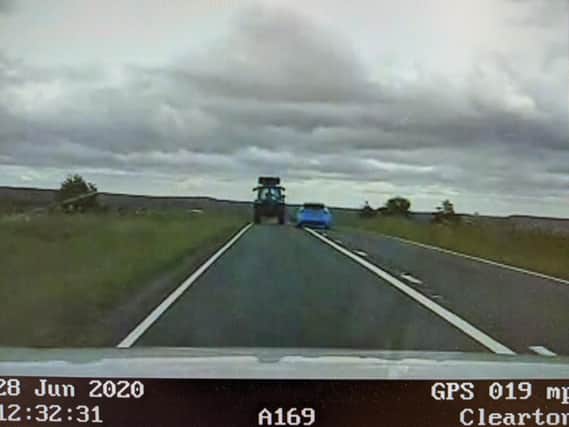 Footage of a car overtaking a tractor on a white line on the A169 near RAF Fylingdales.