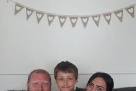 Eli Harrison with his dad Ian and mum Kayleigh. Eli is pictured with a certificate Kayleighs colleagues made for him when they heard about his brave actions.