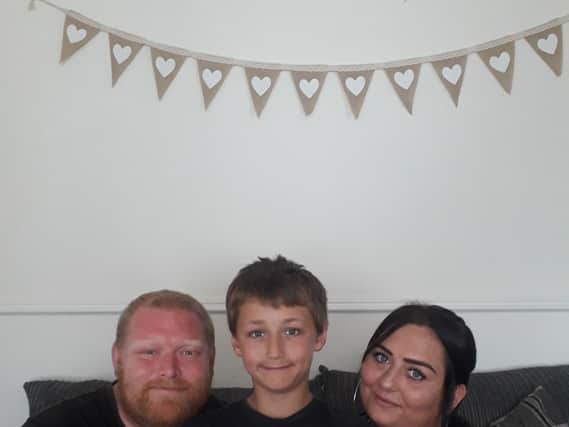 Eli Harrison with his dad Ian and mum Kayleigh. Eli is pictured with a certificate Kayleighs colleagues made for him when they heard about his brave actions.