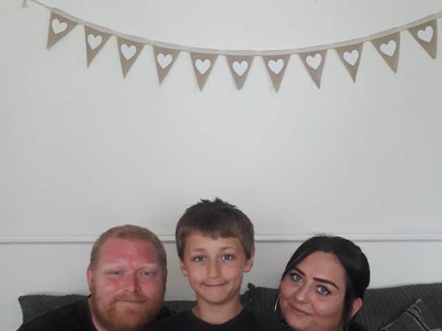 Eli Harrison with his dad Ian and mum Kayleigh. Eli is pictured with a certificate Kayleighs colleagues made for him when they heard about his brave actions.