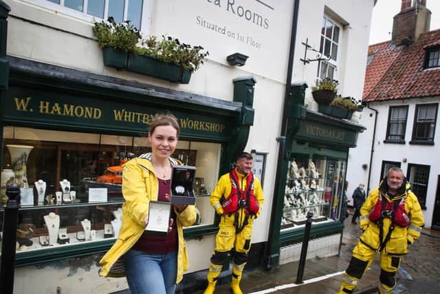 Rebecca Tucker from W Hamond jewellers in Whitby holds the donated jewellery and watch with Whitby RNLI's coxswain Howard Fields and crew member Matt Sharpe.