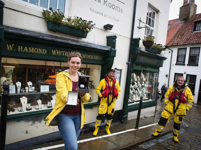 Rebecca Tucker from W Hamond jewellers in Whitby holds the donated jewellery and watch with Whitby RNLI's coxswain Howard Fields and crew member Matt Sharpe.