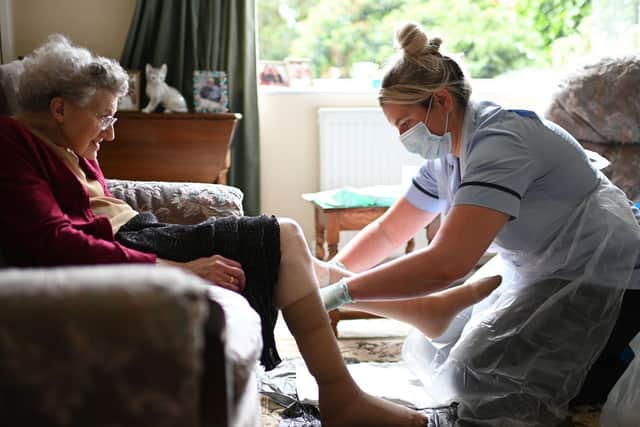 Pictured, a nurse, wearing personal protective equipment (PPE), changing the dressings on the legs of an elderly woman during a home visit in June. Photo credit: PA