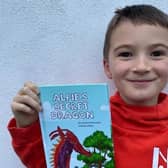 Jacob Carnes, 8, is pictured with his book called Alfie’s Secret Dragon.