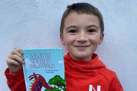 Jacob Carnes, 8, is pictured with his book called Alfie’s Secret Dragon.