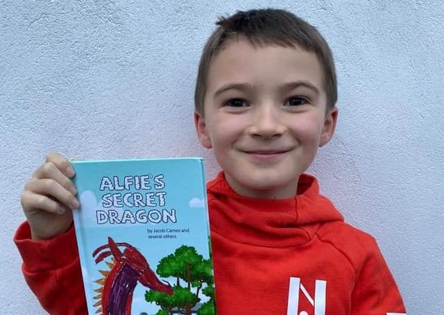 Jacob Carnes, 8, is pictured with his book called Alfie’s Secret Dragon.