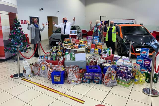 Senior service advisor Maggie McLeod and Centre Principle Peter Stableford hand donations to Trish Kinsella, manager of The Rainbow Centre and her driver.