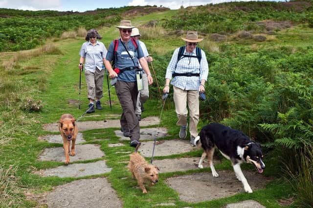 People with dogs on a lead on path at Dundale.