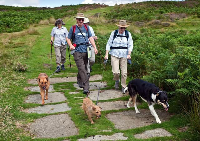 People with dogs on a lead on path at Dundale.