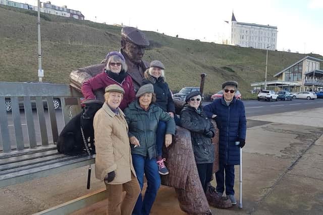 Mary and her walking group in their flat caps at the Freddie Gilroy sculpture.