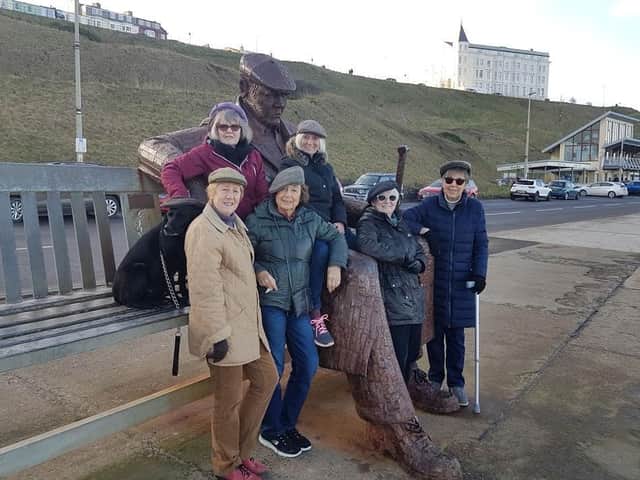 Mary and her walking group in their flat caps at the Freddie Gilroy sculpture.