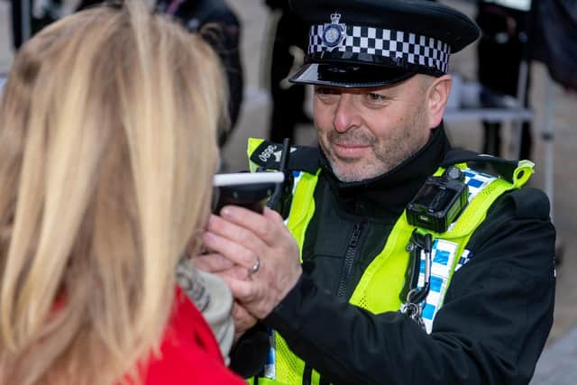 A police officer carries out a drink driving breathalyser test.