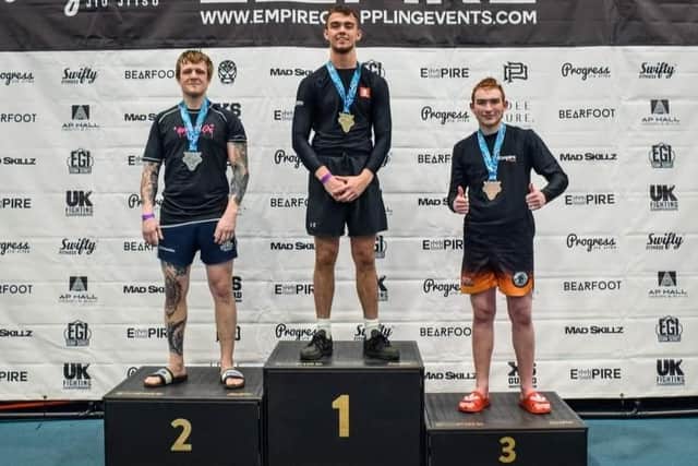 Jack Anderson, left, takes his place on the podium for earning a silver medal in the Beginners under 79.5kg division