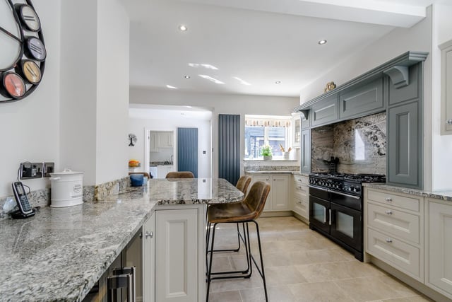 A view through the impressive kitchen that benefits from both natural light and ceiling spotlights.  It includes a large breakfast table, bespoke units and granite work tops.