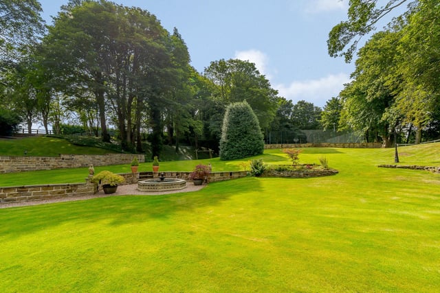 A paved sunken area showcases a water feature within the lawned gardens.