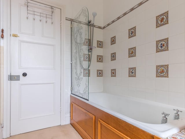 An over bath shower is fitted in this house facility with decorative tiles.