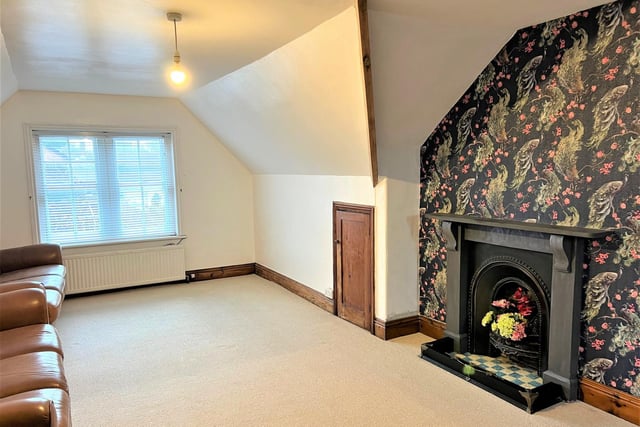 The attic conversion, currently used as a sitting room, with feature wallpaper and another stunning Victorian fireplace.