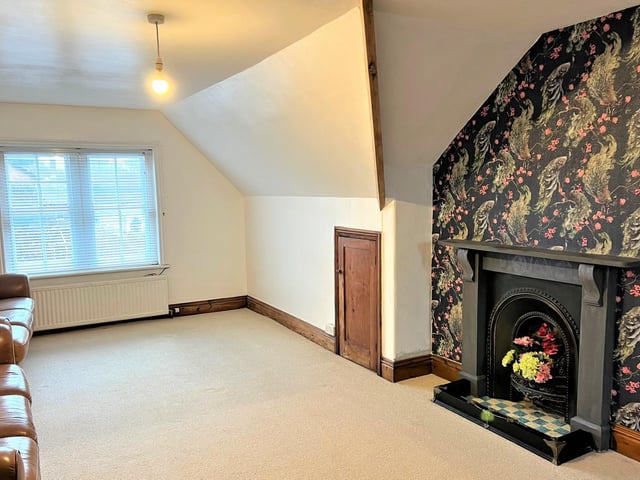 The attic conversion, currently used as a sitting room, with feature wallpaper and another stunning Victorian fireplace.