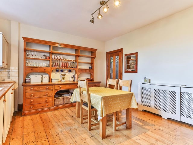 This roomy kitchen has fitted units with wooden work tops, and a large window.