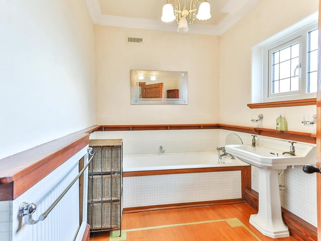 A wood finish adds style to the bathroom, with a larfge bath and wash basin.