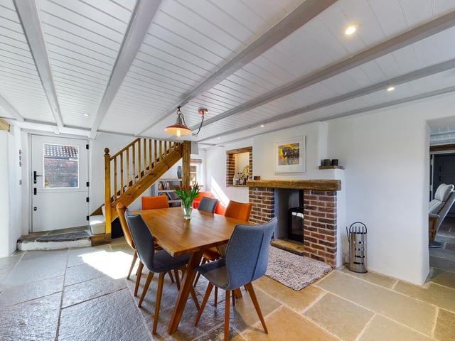 A fireplace and open staircase are features of this room which has enough space for a large dining table and chairs.