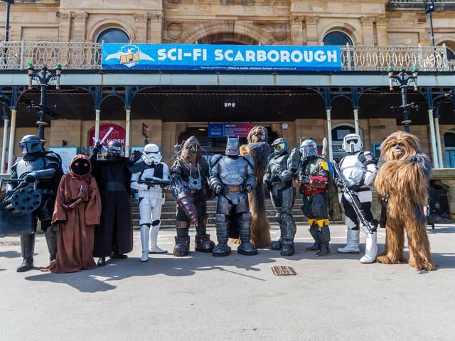 A Mandalorian, a Jawa, Kylo Ren, a Stormtrooper commander, a Big Daddy from Bioshock, Armoured Batman, Chewbacca, Master Chief from Halo, Boba Fett and a biker scout from Star Wars, and another Wookiee gather outside Scarborough Spa.