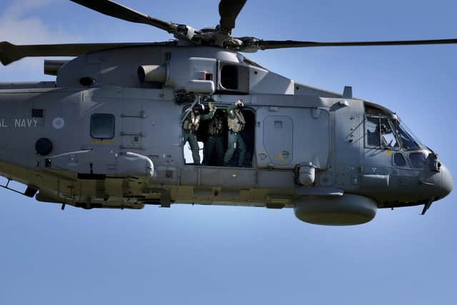 Service personnel wave from the Merlin helicopter flypast.