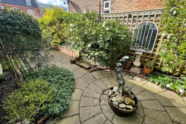 The enclosed garden has mature plants and shrubs, and includes a seating area.