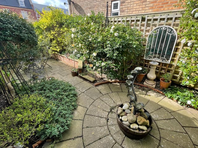 The enclosed garden has mature plants and shrubs, and includes a seating area.