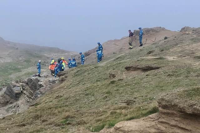 Coastguard Rescue Officers and Lythe Fire and Rescue Officers carrying the casualty to the YAS ambulance.