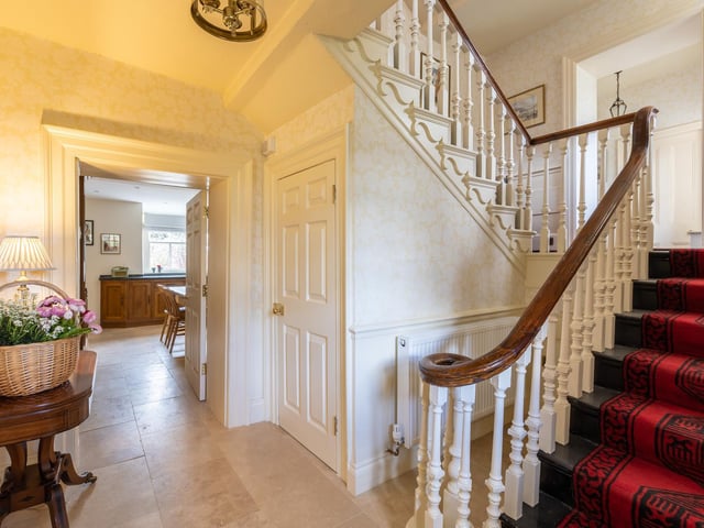 A spacious hallway with feature staircase.
